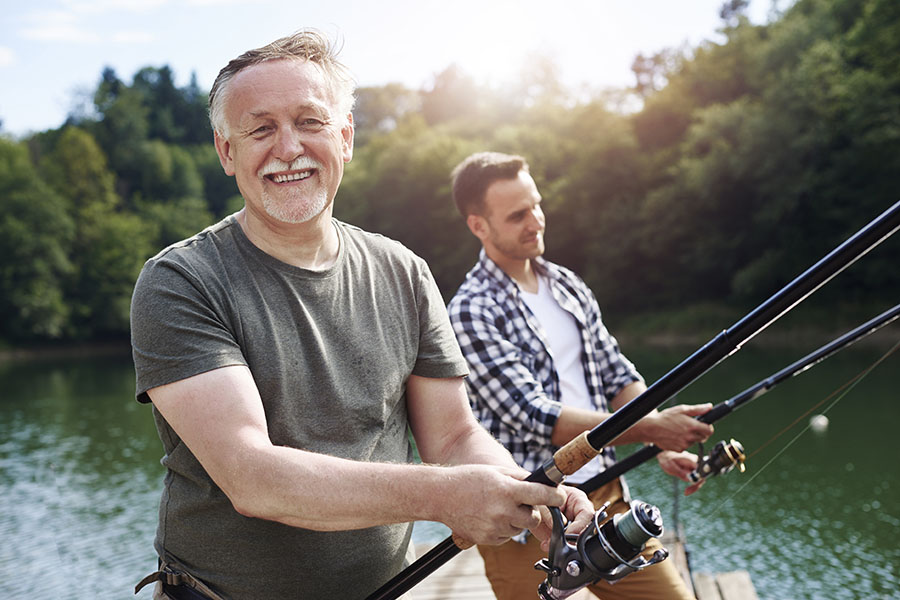 Personal Insurance - Older Man Fishing With Grown Son On A Sunny Day