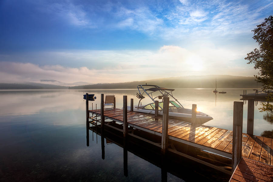 Smithville, MO Insurance - Boat Anchored to a Small Wooden Dock on a Calm Lake at Sunrise With Mist Rising Over the Water